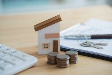 Ev kredisi konsepti. Ev modeli bir emlakçı ve müşteri olarak satın alma, sigortalama ve finanse etme sözleşmelerini tartışırlar. Kredi ekonomisi ticari gayrimenkul yatırımları.