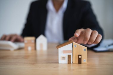 Ev kredisi konsepti. İş adamı poin ev modeli emlakçı ve müşteri satın alma, sigortalama, finanse etme sözleşmelerini tartışıyor. Kredi ekonomisi ticari gayrimenkul yatırımları.