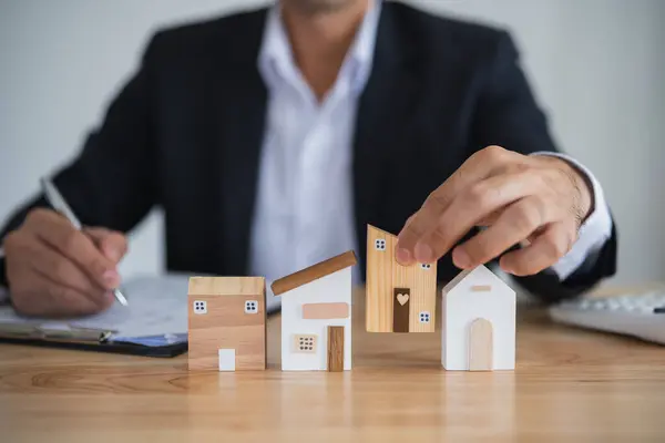 Home loan concept. Business man holding house model real estate agent and customer discuss contracts buying, insuring, financing the property. Loan finance economy commercial real estate investments.