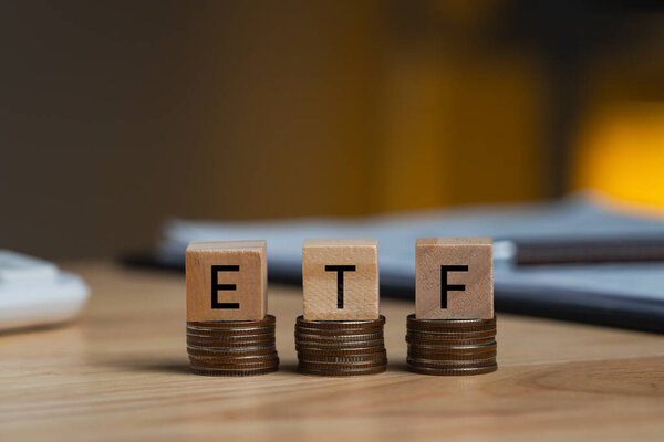 Понятие ETF деревянные блоки на рядах укладывают монеты на стол, аббревиатура ETF, которая относится к биржевому торговому фонду, высеченному на деревянных кубиках долларов США. Экономика и инвестиции.