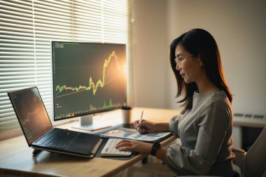 Asyalı İş Kadını, bilgisayar ekranı, kripto para birimi gelecek fiyat öngörüsü üzerinden Bitcoin veya borsa fiyat tablosunu kontrol ediyor. Ticari Hisse Bitcoin ETF.