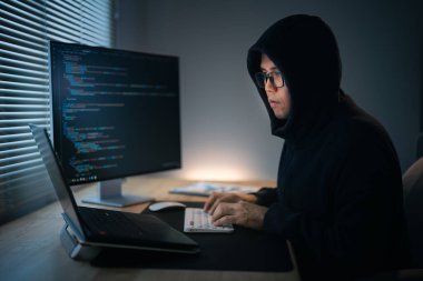 Hacker, Ağ 'ın güvenlik sistemini hacklemek için kapüşon takıyor. Tehlikeli Başlıklı Hacker Hükümet Veri Sunucularına sızıyor ve sistemlerine bir virüs bulaştırıyor. Hackleme ve kötü amaçlı yazılım kavramı.