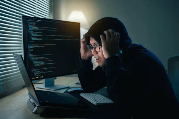 Hacker man wearing glasses and hood depression or serious mistake for hack network security system. Dangerous Hooded Hacker Breaks into Government Data Servers and Infects Their System with a Virus.