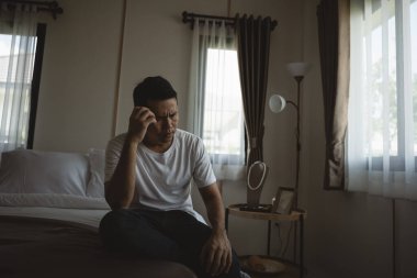 Siluet depresif bir adam yatak odasında yatakta oturuyor. Üzgün Asyalı erkekler uykusuzluk çekiyorlar ve yatak odasında tek başlarına yatıyorlar. Depresyon sağlık insanları kavramı.