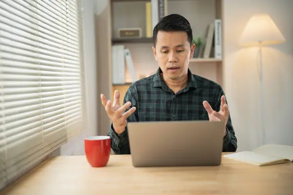 Asian freelance business man working talking making video call in home office, using laptop, talking, watching webinar or studying language, speaking, online training, explaining, e-learning.