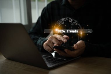 Eğilimler 2024 yıllık konsept. Mobil laptop kullanan ve yeni yılda pazarlama izleme ve iş planlaması için 2024 trend içeren sanal arama motoru çubuğu gösteren bir adam. Teknoloji Yeni Yıl Konsepti.