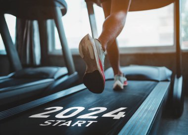Mutlu yıllar 2024 yeni yılın başlangıcını sembolize ediyor. Ayaklarını kapat, spor koşucusu fitness kulübünde koşu bandında koşuyor. Kardiyo çalışması. Sağlıklı yaşam tarzı, spor salonunda erkek eğitimi..