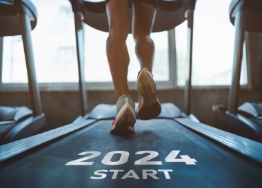 Mutlu yıllar 2024 yeni yılın başlangıcını sembolize ediyor. Ayaklarını kapat, spor koşucusu fitness kulübünde koşu bandında koşuyor. Kardiyo çalışması. Sağlıklı yaşam tarzı, spor salonunda erkek eğitimi..