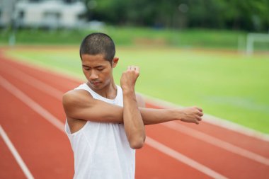 Athletes sport man runner wearing white sportswear to stretching and warm up before practicing on a running track at a stadium. Runner sport concept.