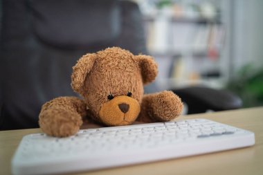 Masada oturan kahverengi ayıcık beyaz klavyede yorgun görünüyor. depresyon hüzünlü kavram.