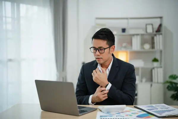 Smart Asian businessman with suit smiling wearing glasses working with computer laptop. concept work form home. Freelance life style, New normal social distancing lifestyle. Work form anywhere concept