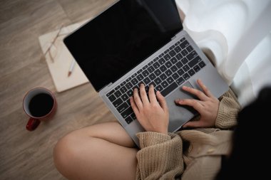 Dizüstü bilgisayarda çalışan, yerde oturan ve bir fincan kahveyle kahve içen kadının ellerini kapat. Ticari serbest konsept.