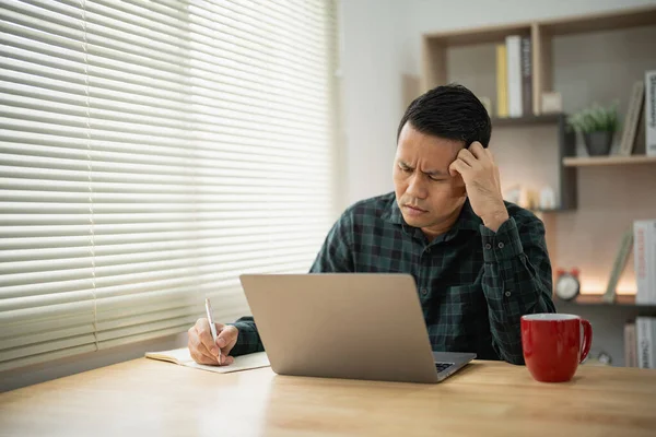 Asian freelance man having stressful depression sad time while working video conferrence meeting on laptop. Depression man sad serios working at home. Work anywhere concept.