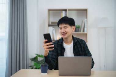 Serbest çalışan bir iş adamı, masada dizüstü bilgisayarla çalışırken cep telefonundan arıyor, müşterilerle görüşmek için iş adamı cep telefonu kullanıyor ya da internetten alışveriş yapıyor. Akıllı telefon görüşmesi konferansı.
