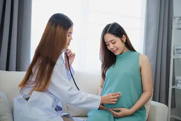 Asian professional woman doctor using stethoscope listening to belly pregnant woman. Medical exam pregnant woman. Healthcare in examination room at hospital or clinic.