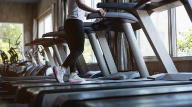Ayaklarını kapat, spor koşucusu fitness kulübünde koşu bandında koşuyor. Kardiyo çalışması. Sağlıklı bir yaşam tarzı, spor salonunda antrenman yapan bir adam. Spor çalıştırma konsepti