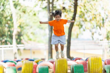 Genç bir kız lastik yığınının üzerinde zıplıyor. Çocuk eğlenirken ve eğlenirken, eğlence ve neşe kavramı