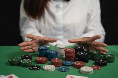 Bir kadın önünde cips yığınıyla poker oynuyor. O beyaz bir gömlek ve siyah bir papyon giyiyor.