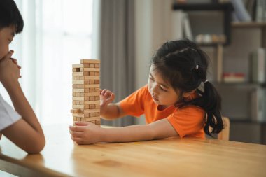 İki çocuk satranç oynuyor. Biri beyaz gömlek giyiyor ve diğeri turuncu gömlek giyiyor.