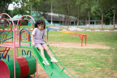 Cute asian girl smile play on school or kindergarten yard or playground. Healthy summer activity for children. Little asian girl climbing outdoors at playground. Child playing on outdoor playground.