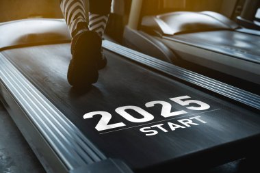 Mutlu yıllar 2025. 2025 yeni yılın başlangıcını simgeliyor. Ayaklarını kapat, spor kadın koşucu fitness kulübünde koşu bandında koşuyor. Kardiyo çalışması. Sağlıklı yaşam tarzı, spor salonunda erkek eğitimi..