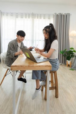 Asyalı Gençler bir ev işyerinde projede işbirliği yapıyor, bir dizüstü bilgisayar kullanıyor ve fikirleri tartışıyorlar, parlak ve modern bir iç tasarım atmosferi var..