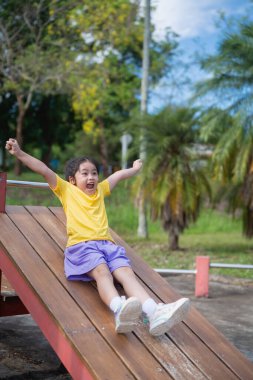 Neşeli Asyalı Çocuk Bahçede Kayıyor Güneşli bir günde Açık Park 'ta Yeşil Ağaçlar ve Mavi Gökyüzü Arkaplanda