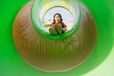 Neşeli Çocuk Renkli Oyun Alanı Kaydırağında Oynuyor. Parlak Yeşil Kuşaklılar, Eğlenceli Açık Hava Aktivitesi Gündüzleri İçeriden Yakalandı.