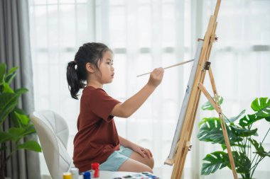 Çocuk Sanatçısı Doğal Işık ve Salon Bitkileriyle Dolu Kapalı Salonda Boya Fırçası ile Tuvalde Başyapıt Oluşturuyor
