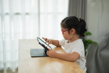 Rahat ev ortamında dijital tabletle meşgul olan küçük çocuk, odaklanmış ifade, öğrenme ve oyun için teknoloji kullanımı, neşeli atmosfer