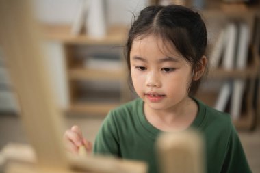 Genç kız resim sehpasında resim yapmaya, sanat stüdyosunda yaratıcı ifadelere, renkli fırça darbelerine, çocukluk yaratıcılığına, sanat ve öğrenme tutkusuna odaklandı.