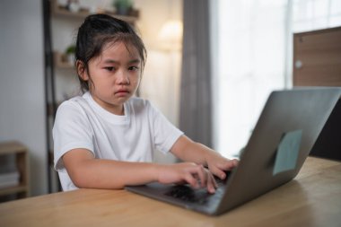 Ev çalışma alanında dizüstü bilgisayarda yazan, rahat bir öğrenme ortamında odaklanma ve kararlılık gösteren, konsantre ifadeli genç bir kız.