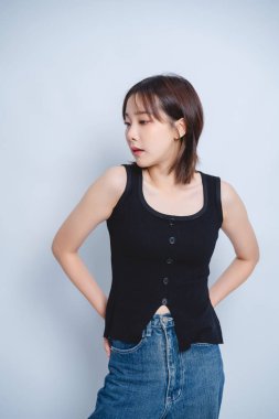 Genç bir kadın modaya uygun siyah atlet ve kot etek modelliği yapıyor, modern stil meraklıları için sıradan ve modaya uygun kıyafetler sergiliyor..