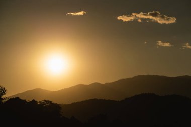 Siluetli Tepeler ve Yumuşak Bulutlu Sıcak Altın Renkli Işıklar Doğa Güzelliğini Ele Geçiren Alacakaranlık Günbatımı