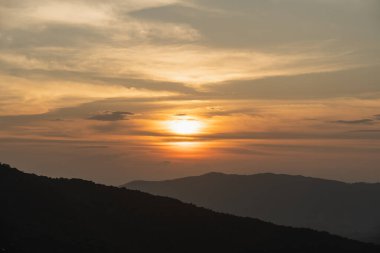 Serene Sunset Over Mountains with Orange and Yellow Skies, Silhouetted by Distant Peaks and calm Atmoshere in the Nature 's Beauty