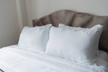 Rahat ve rahat bir yatak, yumuşak beyaz yastıklar ve yumuşak bir battaniye ile dinlenme ve dinlenme için hazırlanan yatak odası.