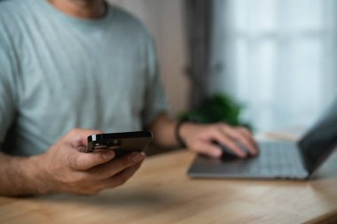 İç İşleri Ofisi Masasında Dizüstü bilgisayar başında Pencere Işığı ve Arka planda Yeşillik ile Çalışan Sıradan Gömlekli Adam