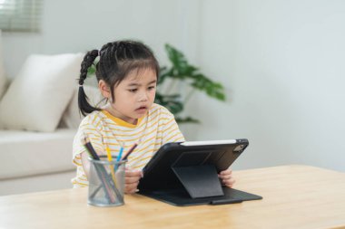 Dijital tabletle meşgul olan genç kız, kırtasiyeli yaratıcı alan, kapalı alan, öğrenme ve teknolojiye odaklanma, eğlenceli atmosfer