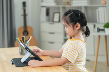 Genç kız evde çevrimiçi öğrenim görüyor, odaklanmış ifadeli tablet kullanıyor, doğal ışıklandırmalı parlak oda, yaratıcı çalışma alanı atmosferi