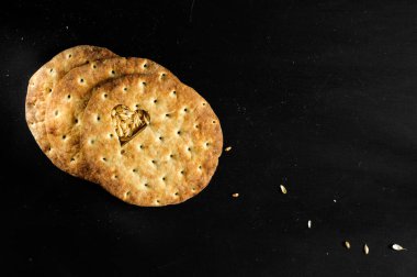 Tahıllı ekmekler ve siyah arka planda kalp şeklinde kesilmiş ana hatlar. Çok geniş alanlı seçici odaklanma. Doğal ışıklandırma