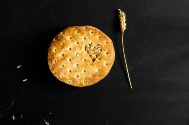 Siyah arka planda ekmek pastası. Kalp şeklinde buğday taneleri. Üst manzara, düz yatış ve doğal ışık