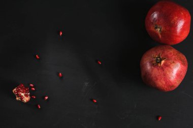 Pomegranate fruits with seeds on a black board. View from above. Selective focus with copy space, daylight