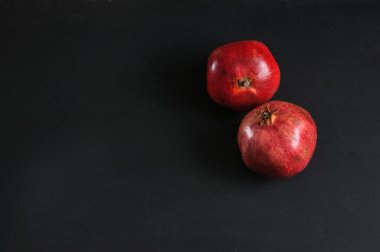 Two ripe pomegranates on a black board, top view. Selective focus with copy space, natural light
