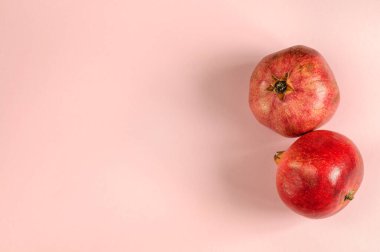 Top view of two ripe pomegranate fruits on a pink background. Selective focus in natural light, free space for text