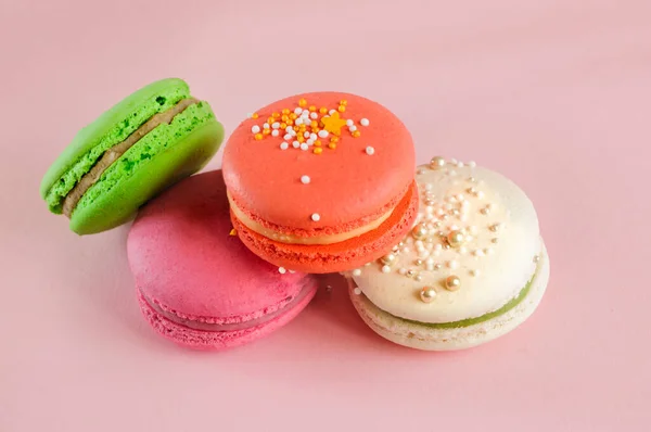 A bunch of fresh macaroons with decor, on a light pink background. High angle view, natural light, selective focus