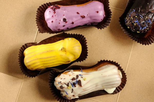 Assorted colored cake eclairs with different flavors and additives. Top view, selective focus