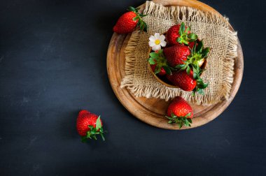 Koyu arkaplanı olan ahşap bir tezgahta çilek manzarası. Kopyalama alanı ile doğal ışıklandırma