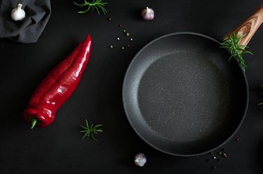 Boş kızartma tavası, sebzeler, otlar ve eski püskü siyah bir arka planda baharatlar. Yukarıdan bak. Doğal ışıkta seçici odak