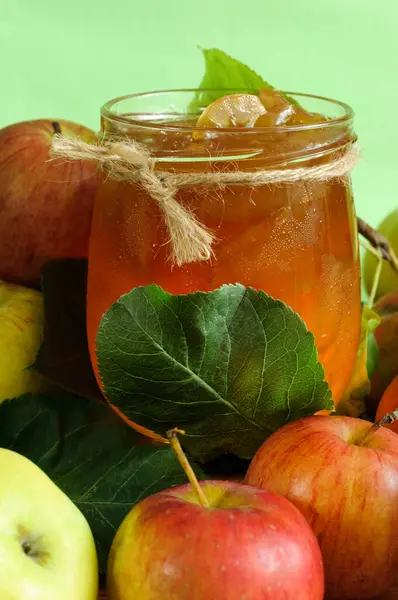Apple jam in a transparent jar with apples and leaves. Selective focus in natural light. vertical image