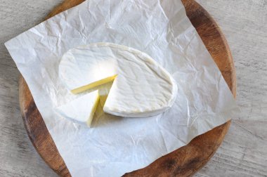 Yumuşak brie peyniri kağıt ve ahşap tahtaya yakın kesilmiş, üst görünüm, gün ışığında seçici odaklanma